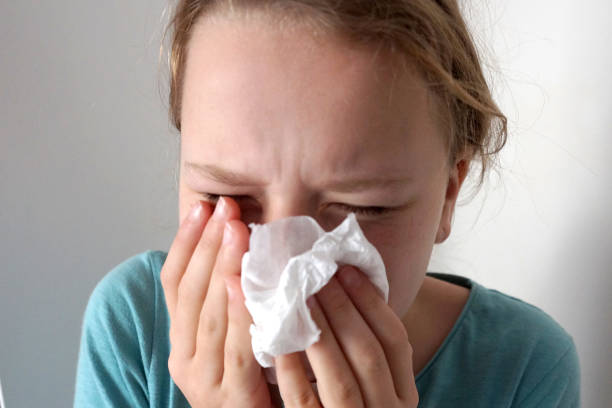 istock girl sneezes into a napkin 1215484671