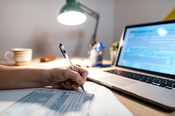 istock Tax form filling on paper or using online service 1215490301