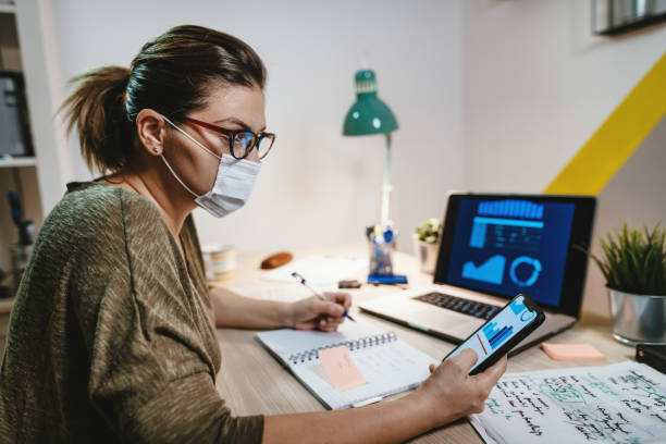 istock Financial advisor trading stocks from home, wearing face mask 1215490413