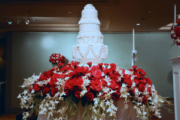 a big 4 layers wedding cake stand on a table of flowers in center of hall for party