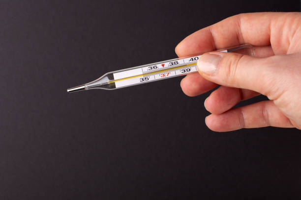 istock Thermometer in hand on a black background. High temperature concept., 1215491489