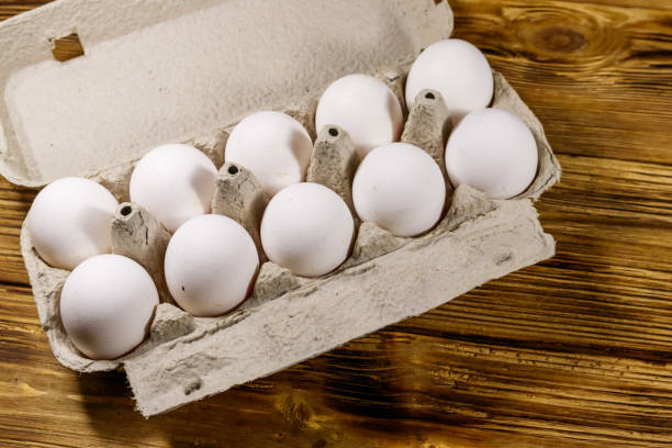 ovos de frango crus em caixa de ovos de papelão em mesa de madeira - 2772 - fotografias e filmes do acervo