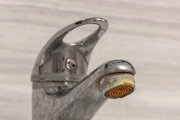 Old Bathroom Sink Faucet contaminated with calcium, grime and rust. Hard water stain build-up.