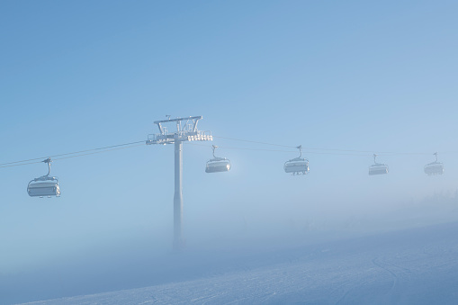 Ski lift along a ski slope at Hafjell ski resort, near Lillehammer, in Norway on a misty winter day in late January.