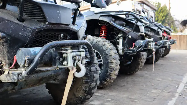 Photo of Many parked ATVs on a dirt road, close up. four-wheel car, all-terrain vehicle. large wheels with powerful legs. Mountain tour in the Carpathians