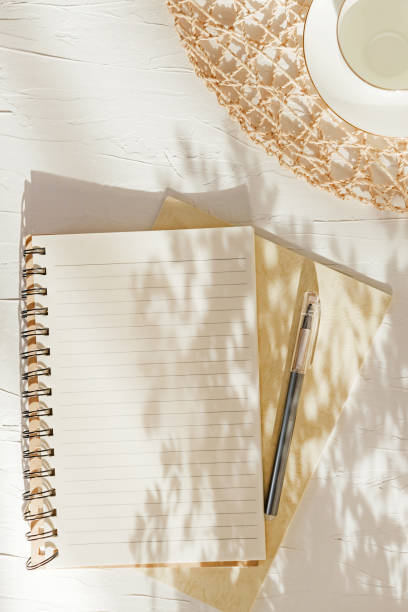istock Summer background White empty cup and blank notebook with pen on the table in the light of the morning sun 1215503607