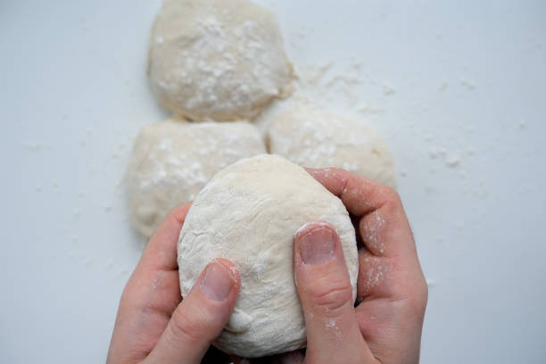 istock Hands of a man rolling fresh, raw dough into round balls 1215505267