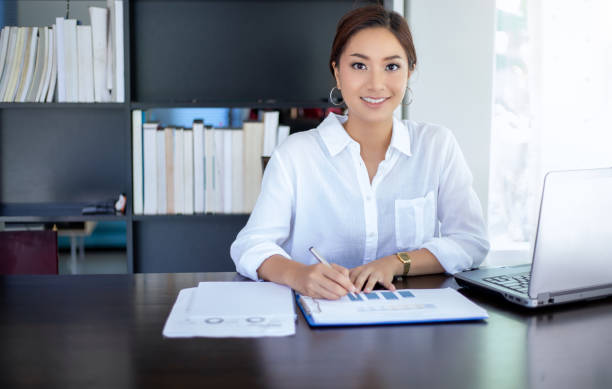 istock Beautiful Asian business women checking document and using notebook working from home for social distance and self responsibility concept 1215507196