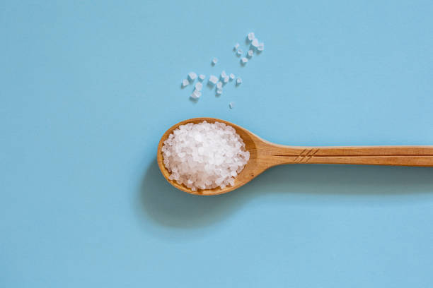 istock Coarse sea salt in a wooden spoon on a blue background. 1215510041