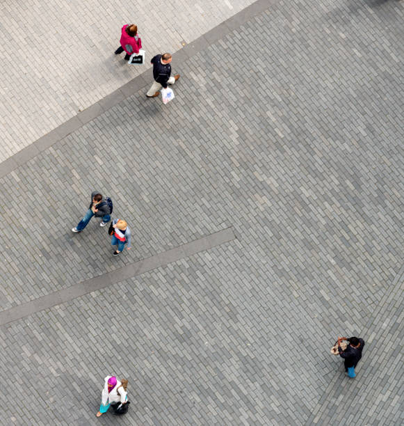 Birmingham, UK - A view of people from directly above, with individuals and couples walking at a distance from each other.