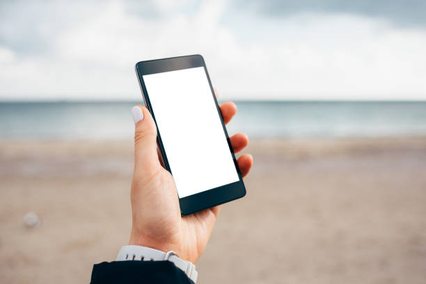 istock Mobile phone in female hand on sand beach background 1215512855