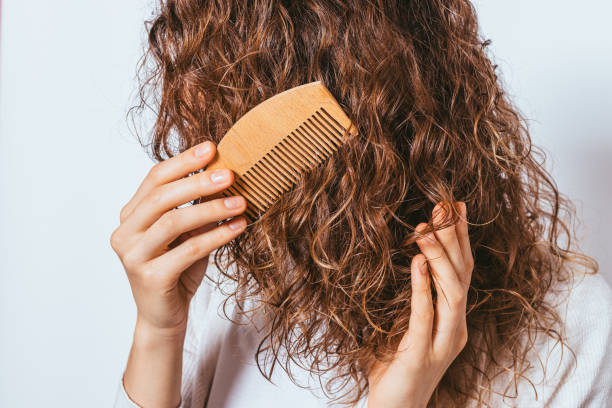 istock Close-up young woman combing her curly hair 1215512947