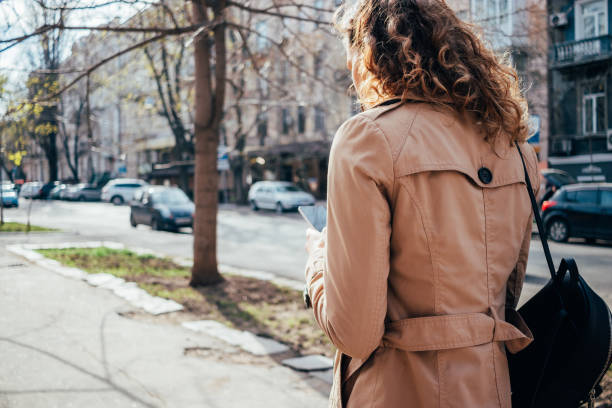 istock Female wearing beige coat typing text messages on mobile device 1215512956