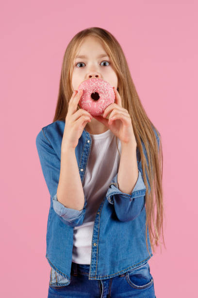 istock girl playing with a donut on a pink background 1215513700