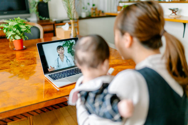 madre con il suo bambino videochiachia con il medico da casa - consultant explaining computer home interior foto e immagini stock