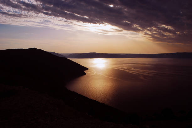 istock the sun sets over the sea behind the clouds 1215516143