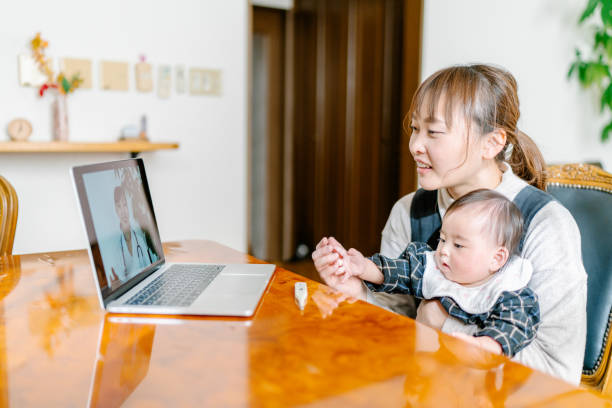 madre con il suo bambino videochiachia con il medico da casa - consultant explaining computer home interior foto e immagini stock