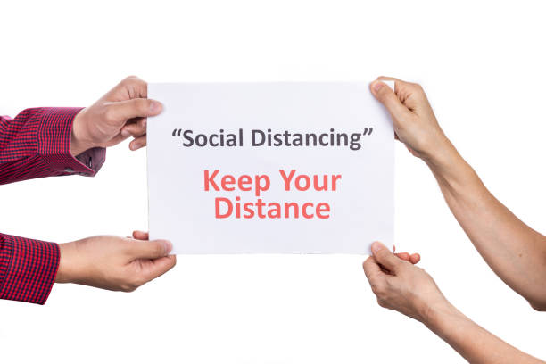 istock Two person holding placard with Social Distancing, Keep Your Distance words. 1215517467