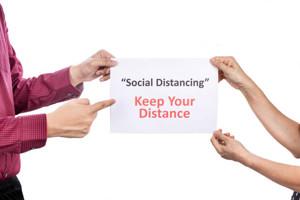 istock Two person holding placard with Social Distancing, Keep Your Distance words. 1215517480
