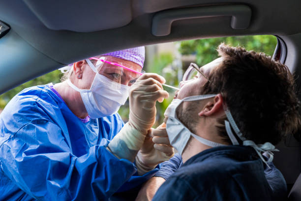 A doctor taking a nasal swab from a driver A doctor in a protective suit taking a nasal swab from a person to test for possible coronavirus infection cotton swab photos stock pictures, royalty-free photos & images
