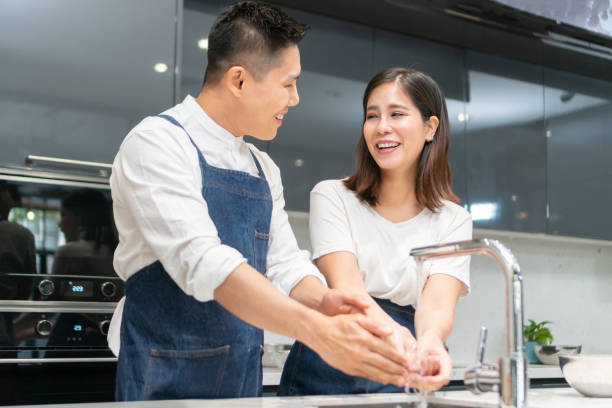 istock Asian couple washing hands with foam soap before cooking together. 1215520533