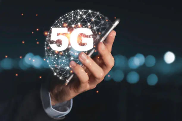 Photo of Businessman holding mobile phone with 5G infographic. 5 Generation wireless technology of mobile signal which big change for internet of thing.