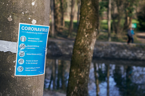 Munich, Germany - March 28, 2020: a note in German in the green areas of the city to inform the citizens of the safety measures to be taken due to covid-19 Coronavirus. The measures include social distancing and hygiene recommendations.