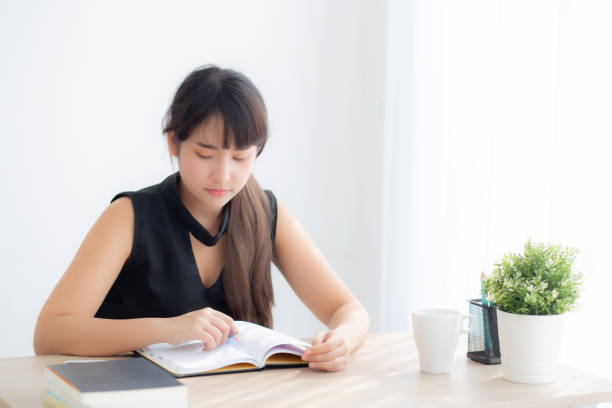 istock Beautiful young asian woman smiling sitting study and learning writing notebook and diary in the living room at home, girl homework, business woman working on table, education concept. 1215522276