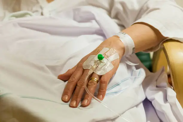 Female patient in hospital getting treatment by peripheral intravenous transfusion catheter. Real people closeup of hand and arm. Caucasian woman at a maternity ward after giving birth, Swedish hospital in Stockholm Sweden.