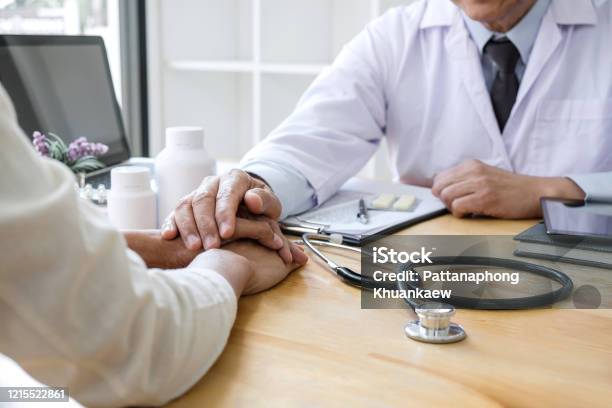 Professor Doctor Touching Patient Hand For Encouragement And Empathy On The Hospital Cheering And Support Patient Bad News Medical Examination Trust And Ethics Stock Photo - Download Image Now