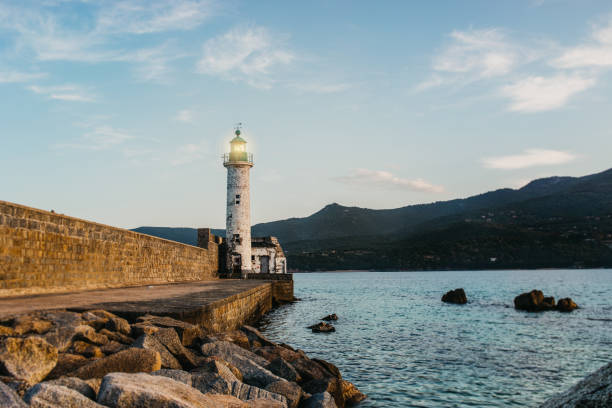 lighthouse at the coast of corsica next to a brickwall blue sky
