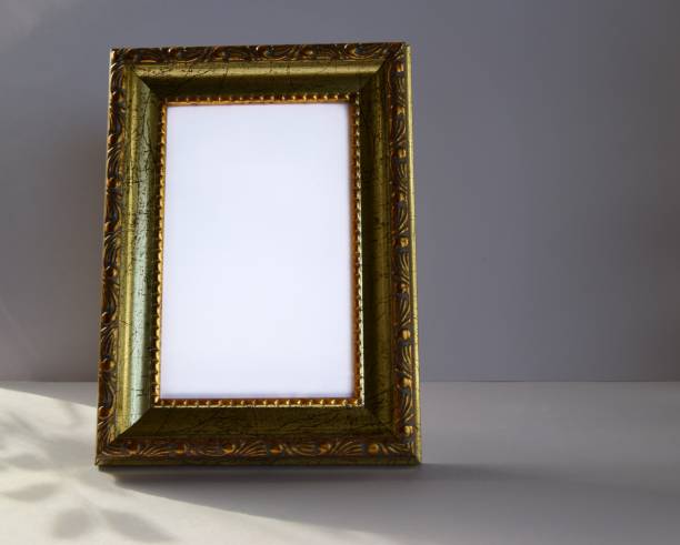 istock Small wooden frame in gold with a light background for inscriptions on a gray background. 1215528767