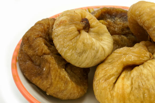 istock Dried figs on a ceramic saucer isolated on white background. Energy and fiber natural source. Dieting food. 1215529283