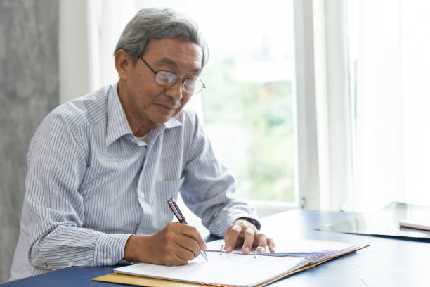 istock Asian smart business elder writing document report in the office. 1215530165