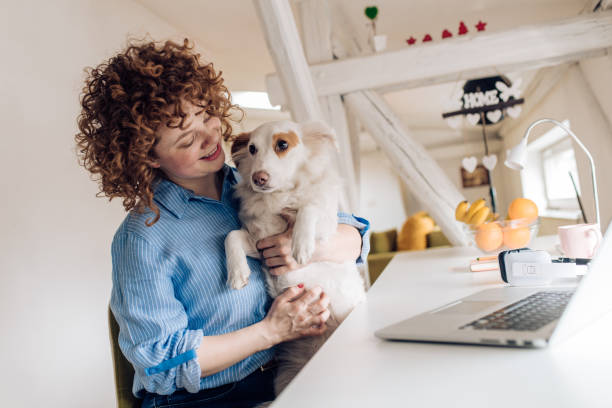 istock Young woman in home isolation working and cuddling her dog 1215533356
