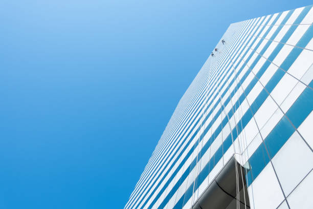 istock Group of workers cleaner cleaning windows on high rise building skyscraper  over blue sky 1215533424