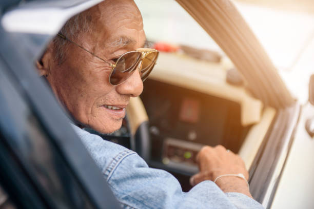 istock Elderly Asian men in denim jacket driving vintage car 1215533520