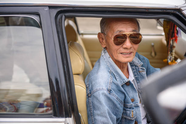istock Elderly Asian men in denim jacket driving vintage car 1215533686