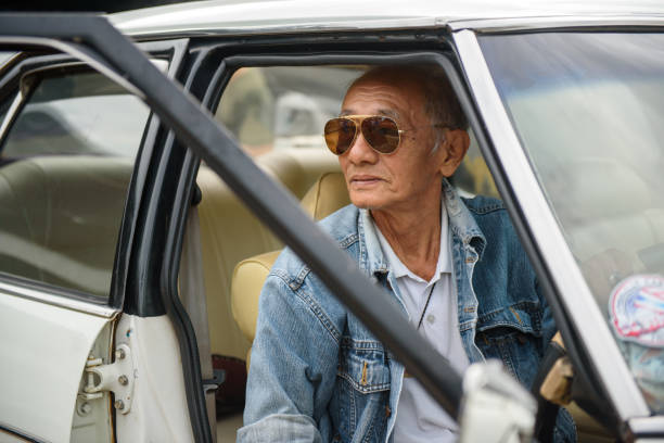 istock Elderly Asian men in denim jacket driving vintage car 1215533689