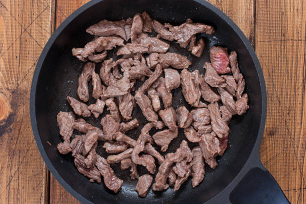 istock Step-by-step preparation of beef stroganoff, step 2 - frying beef cut into pieces, top view, selective focus 1215537487