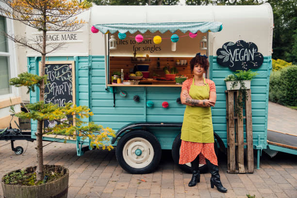 Ready For Business Outside a food truck where a mixed race female hipster stands confidently in front of the truck looking to the camera with her arms folded in front of her. veganism photos stock pictures, royalty-free photos & images