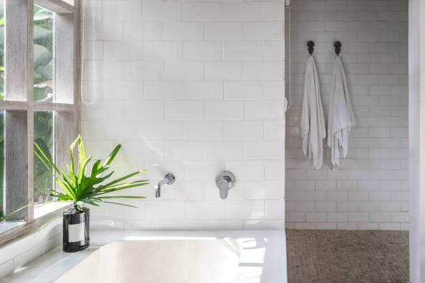 istock White bathroom interior, built bathtub, vase on top near wooden window frame 1215538565