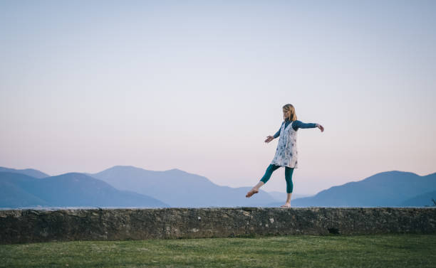 Female dancer performs dancing moves while balancing on ledge Mountains distant cropped pants photos stock pictures, royalty-free photos & images