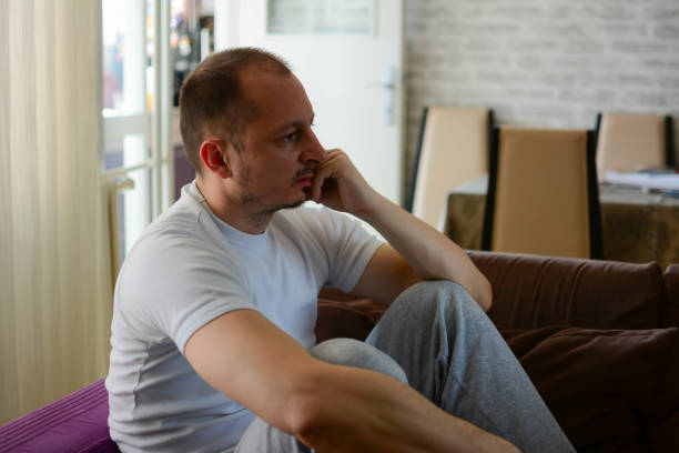 istock Worried man sitting on sofa with hand on head 1215540759