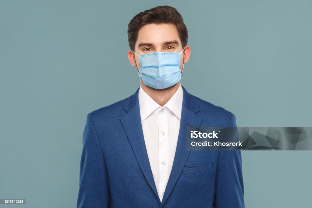 Portret van knappe jonge zakenman met chirurgisch medisch masker dat camera bekijkt. - Royalty-free Beschermend masker - Werkkleding Stockfoto Portret van knappe jonge zakenman met chirurgisch medisch masker dat camera bekijkt. - Royalty-free Beschermend masker - Werkkleding Stockfoto