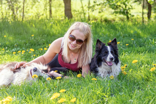 istock Smiling young blond woman with sunglasses lying between two dogs 1215542490