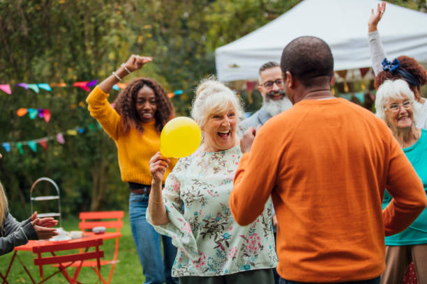 Fun At The Party A multi ethnic group of friends enjoy dancing in the garden at an autumn tea party. Colorful bunting and balloons decorate the garden. fall picnic table stock pictures, royalty-free photos & images