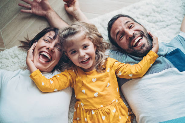 Happy family with a little girl lying on the floor Fun portrait of two parents and a small girl family with one child stock pictures, royalty-free photos & images