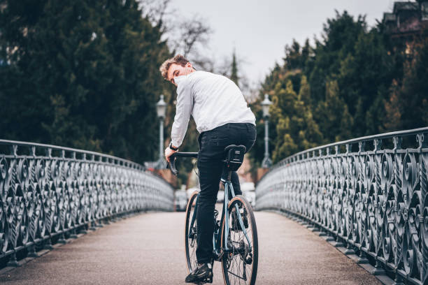 Young man rides bicycle across bridge