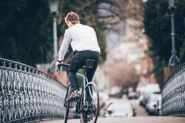 istock Young man rides bicycle across bridge 1215544618